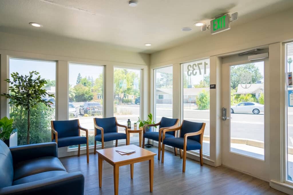 The bright, modern, and welcoming waiting area of Dr. Tex Mabalon’s Sacramento dental practice with blue chairs and large windows.
